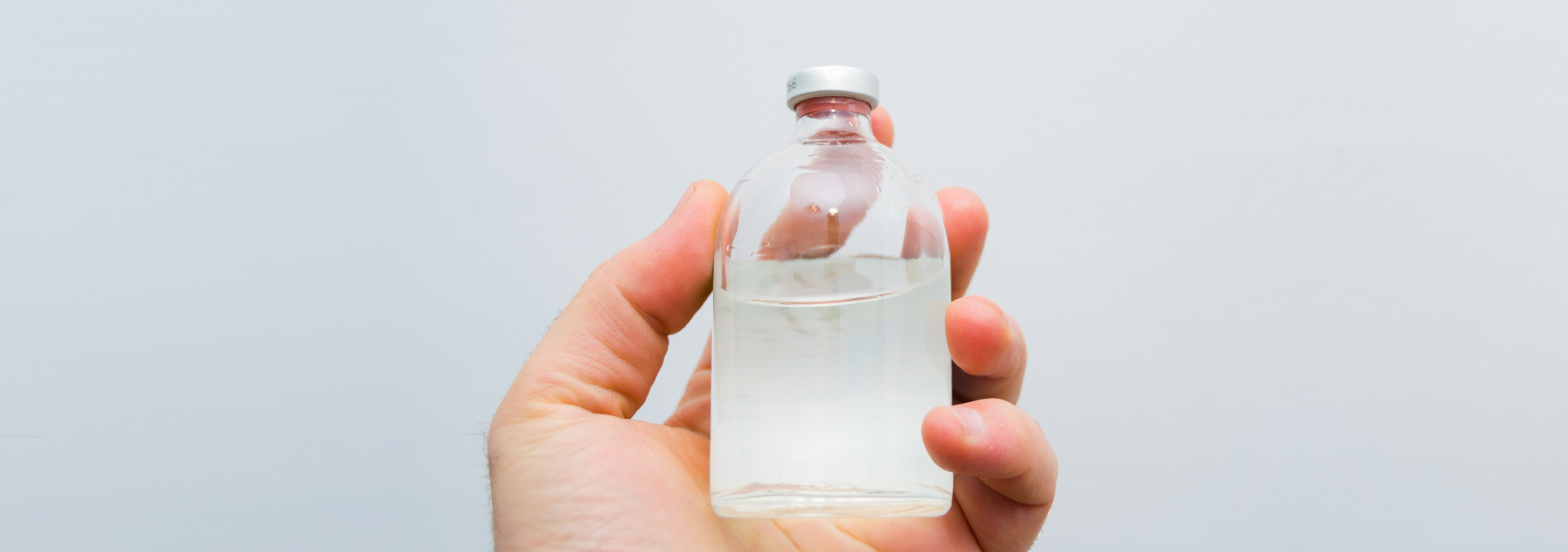 vial with transparent drug solution in a man's hand
